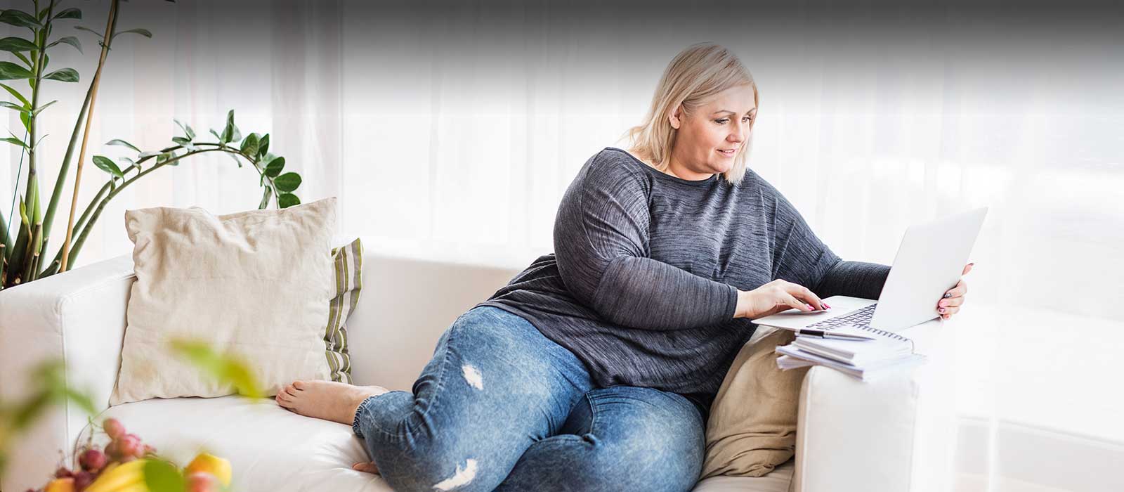 Mature woman on sofa typing on laptop
