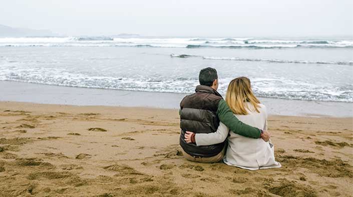 Couple sitting at beach in the fall season