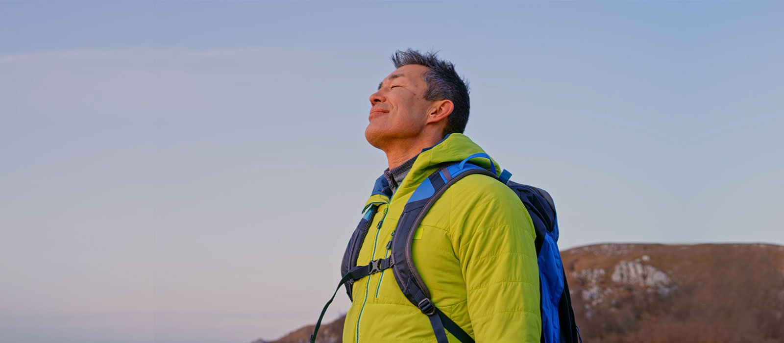 Grateful man breathing deeply on top of mountain