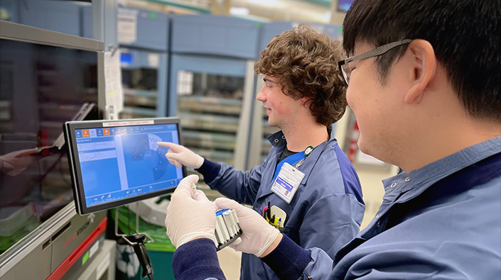 Two male lab team members viewing monitors
