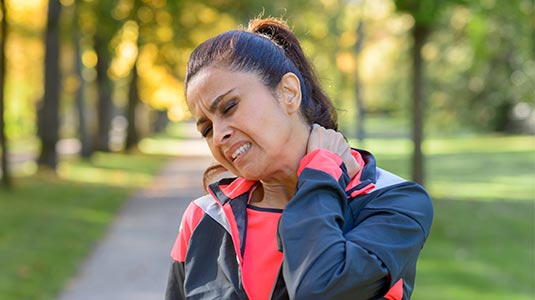 lady on walking path rubbing her sore neck