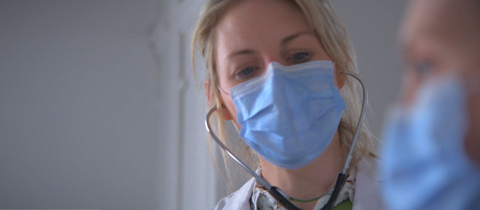 Physician wearing protective mask examining patient.