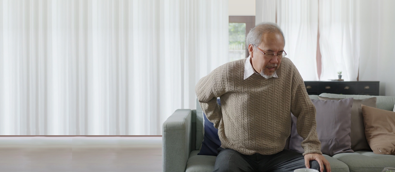 elderly asian man holding his back