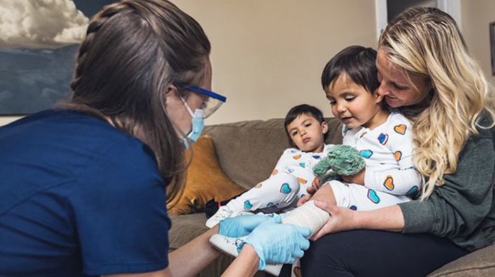 mom holding child on lap while doctor wraps ankle in bandage