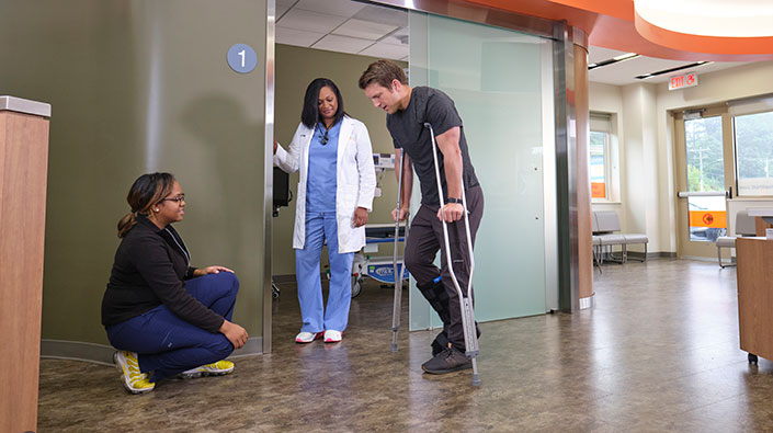 providers assisting a patient on crutches