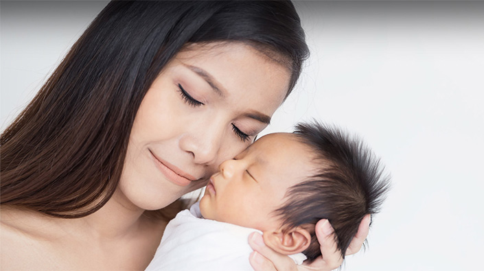 Asian woman holding newborn