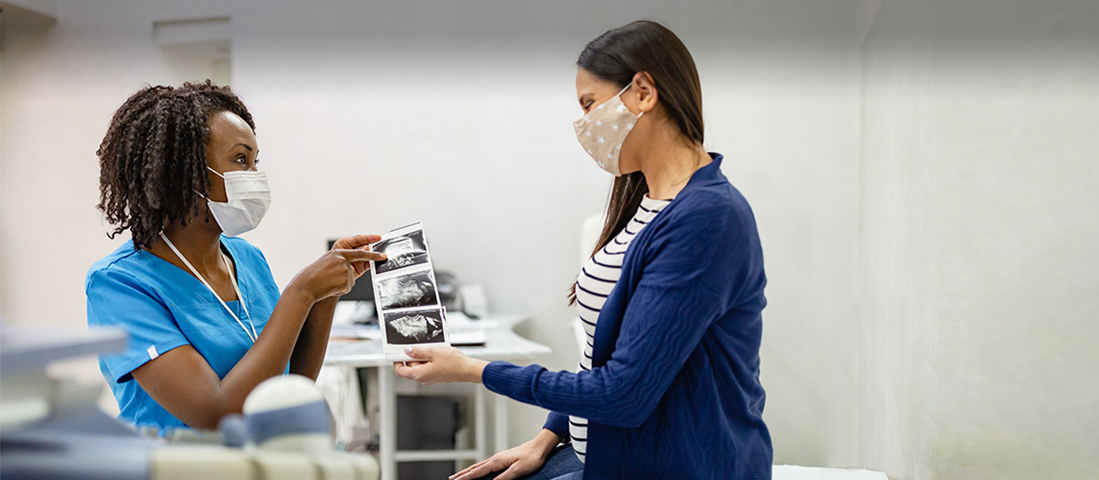 Pregnant woman reviewing sonograph image with nurse