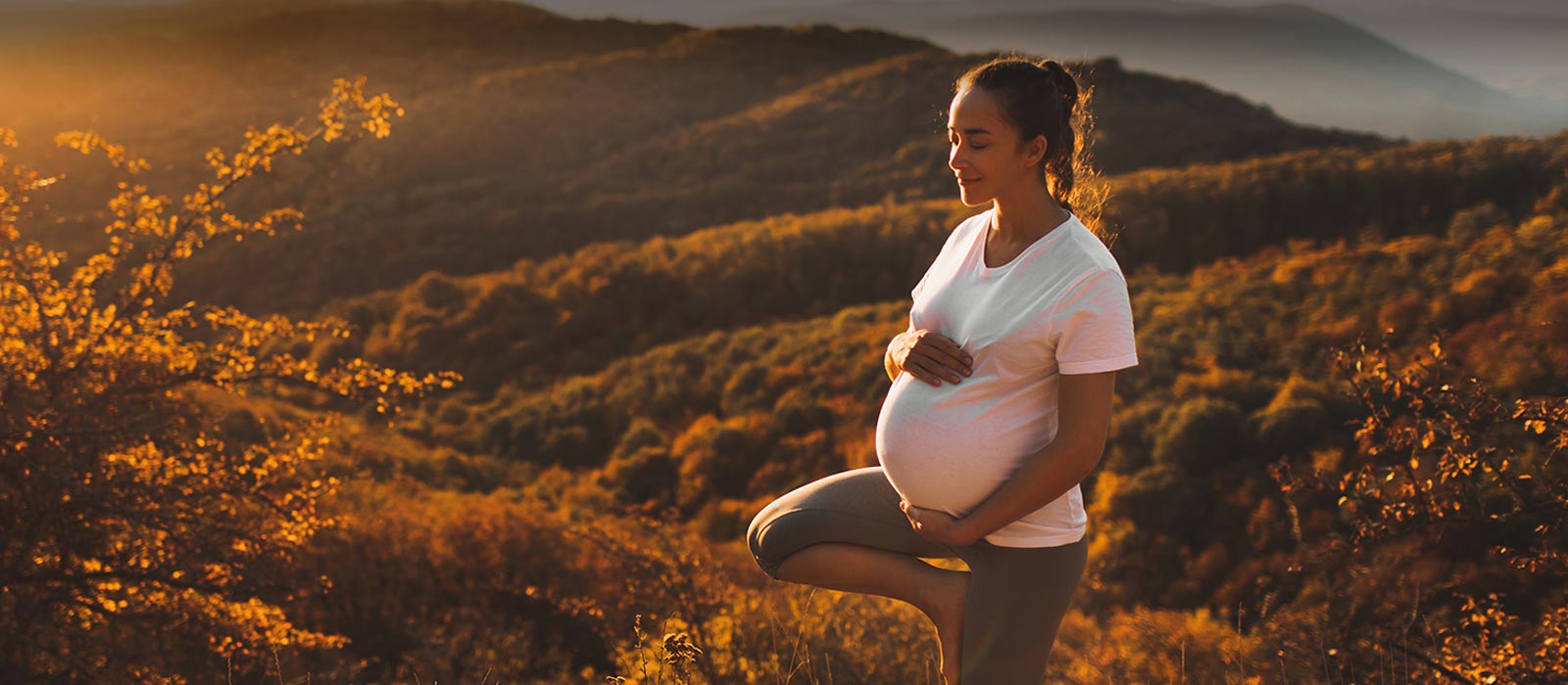Pregnant woman outdoors practicing yoga