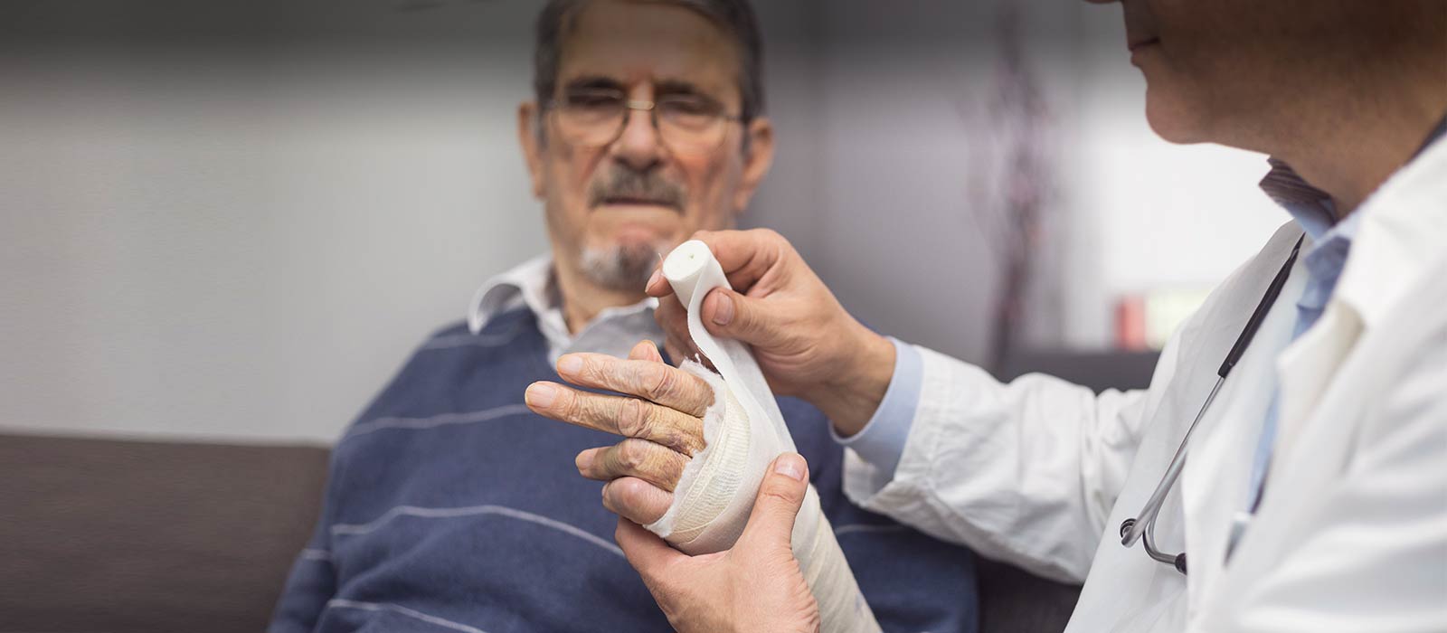 Doctor bandaging senior man's arm wound