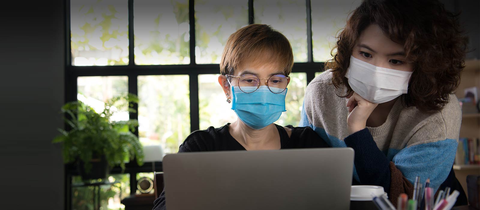 Asian daughter and mother viewing laptop