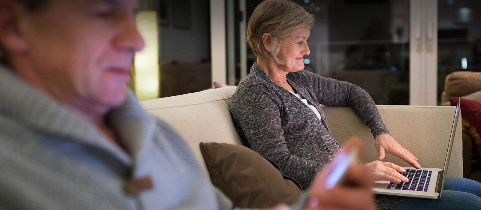 Mature couple reading on devices at home