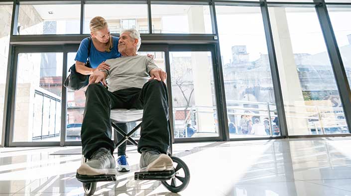 Senior patient in wheelchair at hospital lobby.