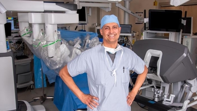 Ramesh Singh, MD posing front of surgical robot