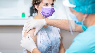 woman wearing mask receiving flu shot