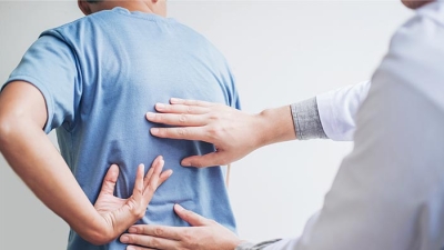 Spine specialist examining patient's lower back.