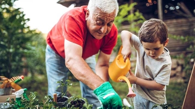 Senior man and grandson watering garden