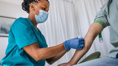 Clinical worker drawing blood from patient
