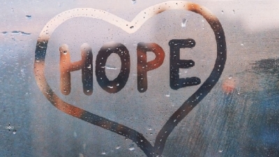 the word Hope inside a heart written in fog on a window