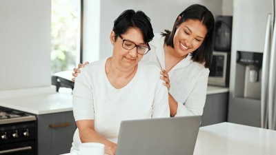 Mature mother and daughter using laptop