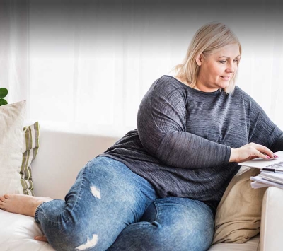 Mature woman on sofa typing on laptop