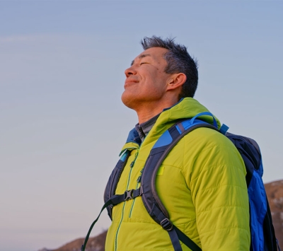 Grateful man breathing deeply on top of mountain