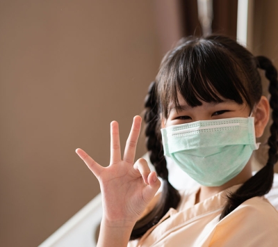 young girl wearing protective mask in hospital bed