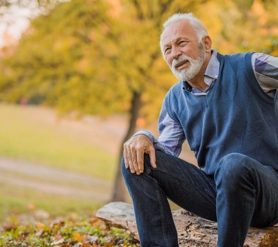 older man outside holding his sore back