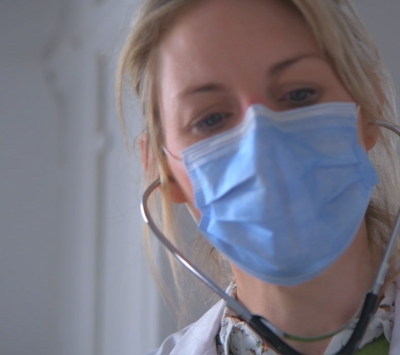 Physician wearing protective mask examining patient.