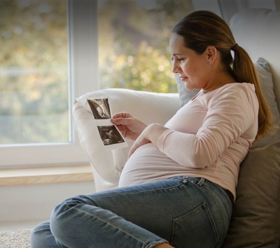 Pregnant woman holding sonogram image