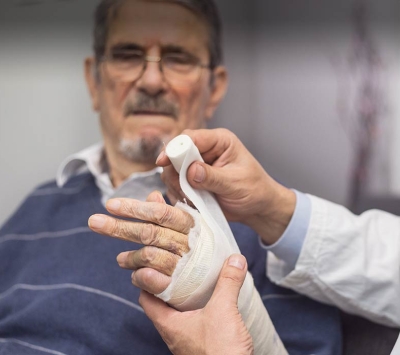 Doctor bandaging senior man's arm wound