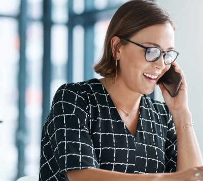 Woman talking on smartphone and using laptop