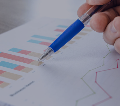 hand holding a pen over graphs on paper
