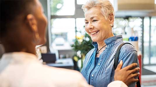 Mature woman greeted by clinical worker