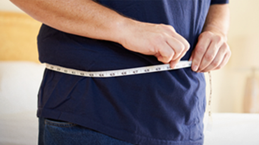 person holding measuring tape around waist