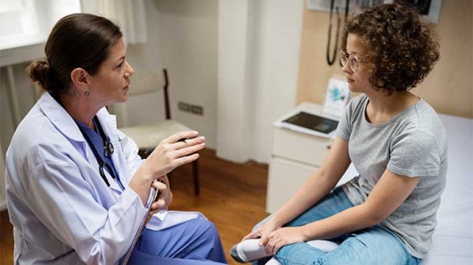 doctor talking with a teen girl in a hospital room