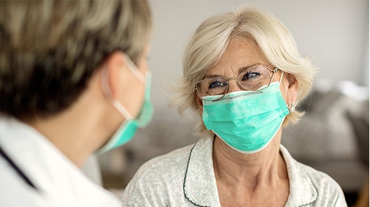 Doctor with grateful patient wearing masks