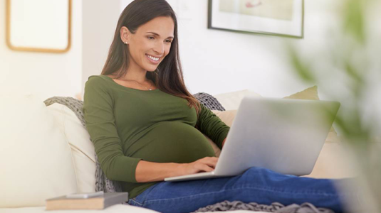 pregnant mom using laptop on couch