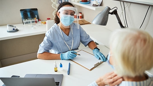 nurse with face mask having consult with female patient