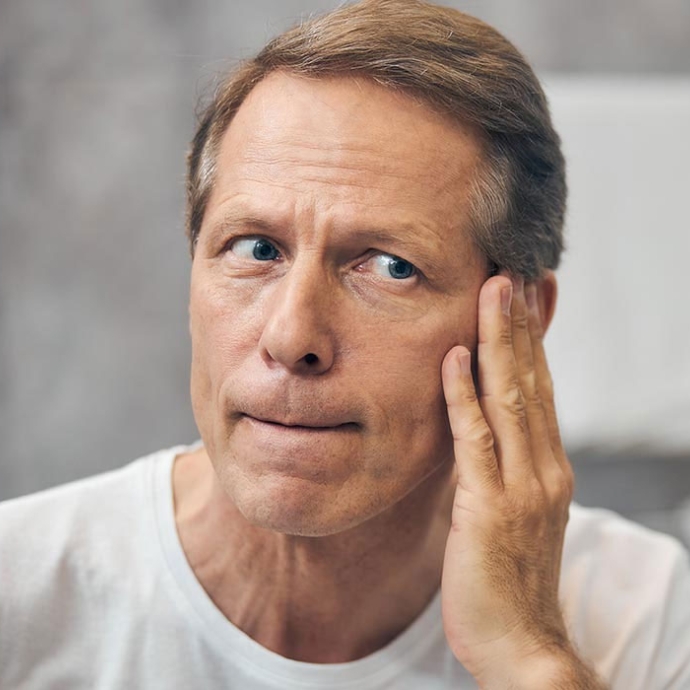 man checking skin in mirror